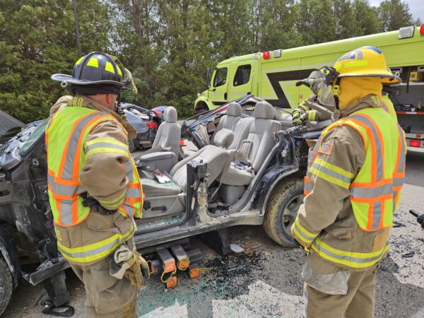 Firefighters assessing a heavily damaged vehicle after an accident.