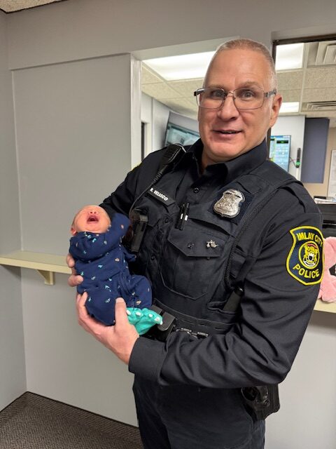Police officer holding a baby in uniform