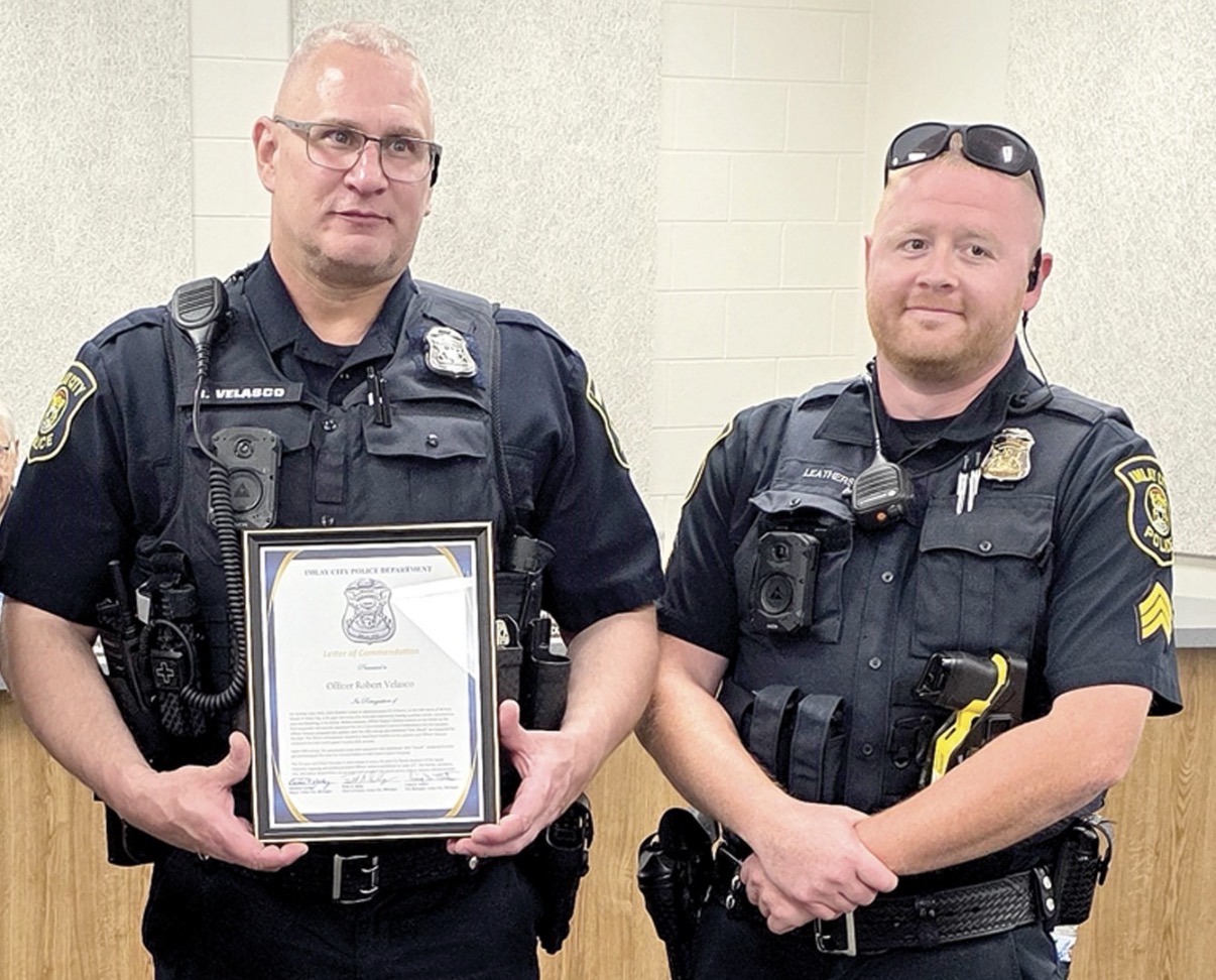 Two police officers with a framed certificate.